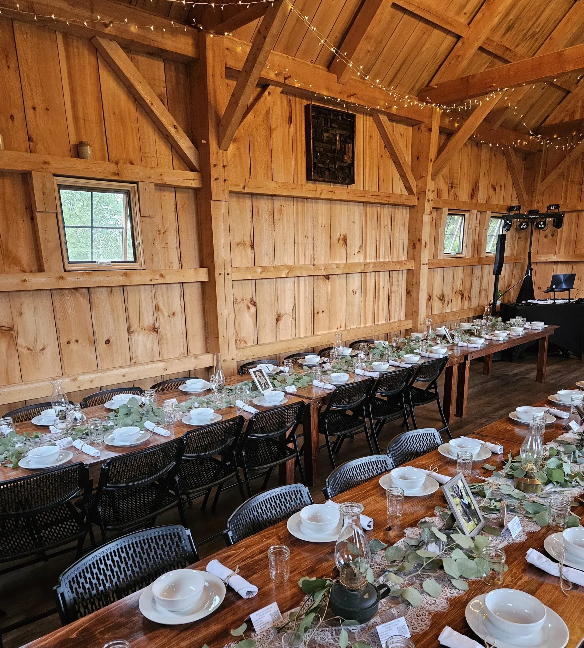Farm tables dress with a lace table runner and white plates inside an authentic maine barn